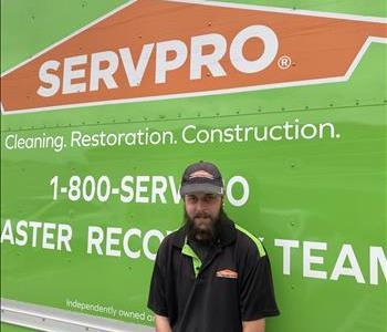 Male employee Paul Taggart standing in front of a green wall with the SERVPRO logo on it.