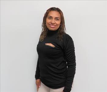 Female employee Norma Ortiz standing in front of a muted wall