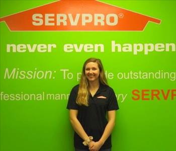 Female employee Brittany Paff standing in front of a green wall with the SERVPRO logo