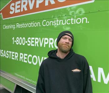 Male employee John Minter standing in front of a SERVPRO vehicle