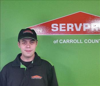Male employee Paul Taggart standing in front of a green wall with the SERVPRO logo on it.