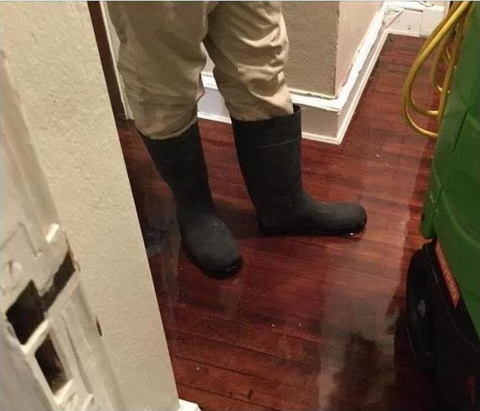 Person standing in their flooded home wearing rainboots