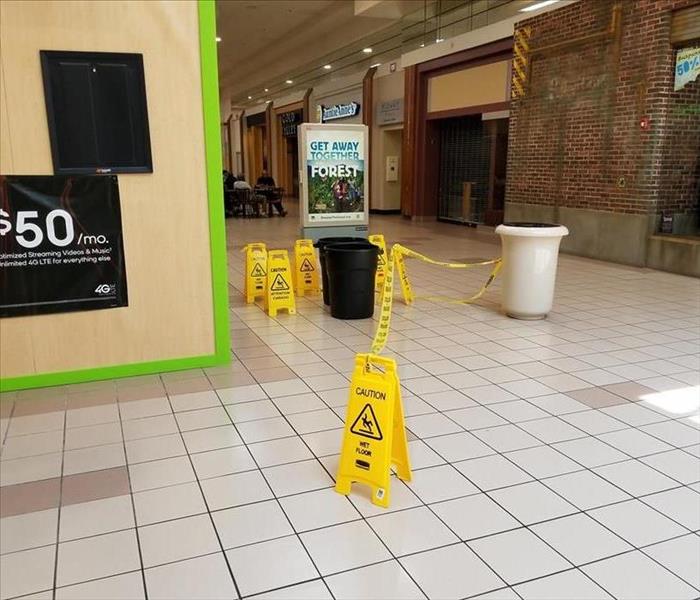 Trashcans and wet floor signs being used to mitigate a roof leak